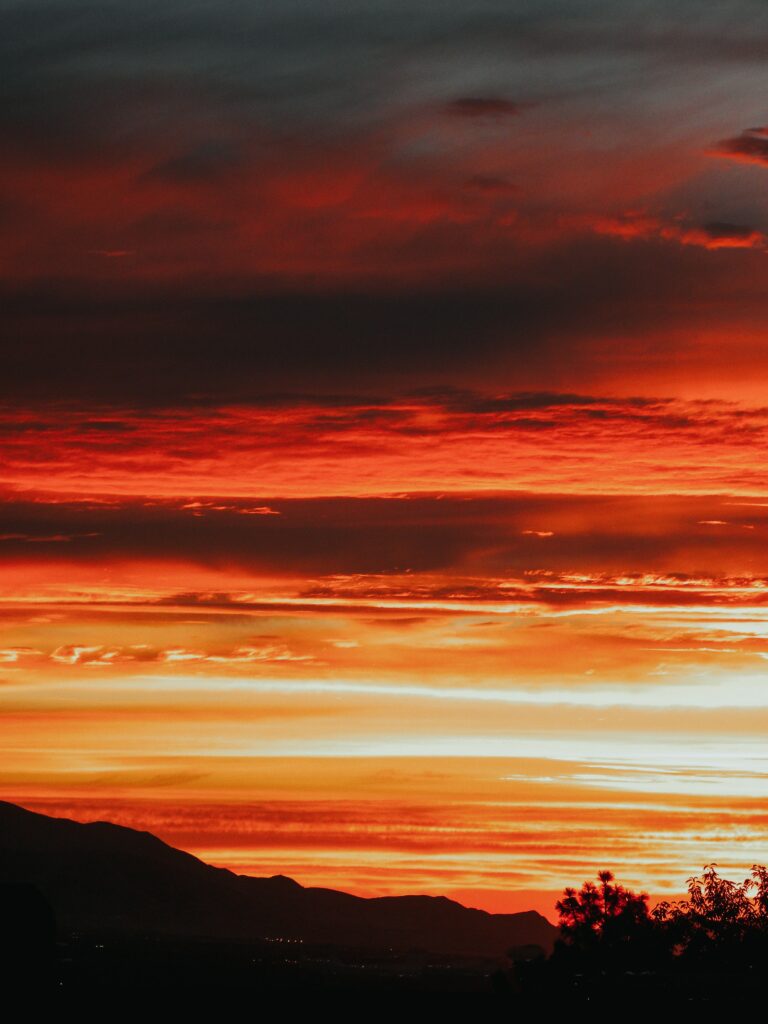 Sunset wallpaper with vibrant orange and red clouds fading into dark evening sky background
