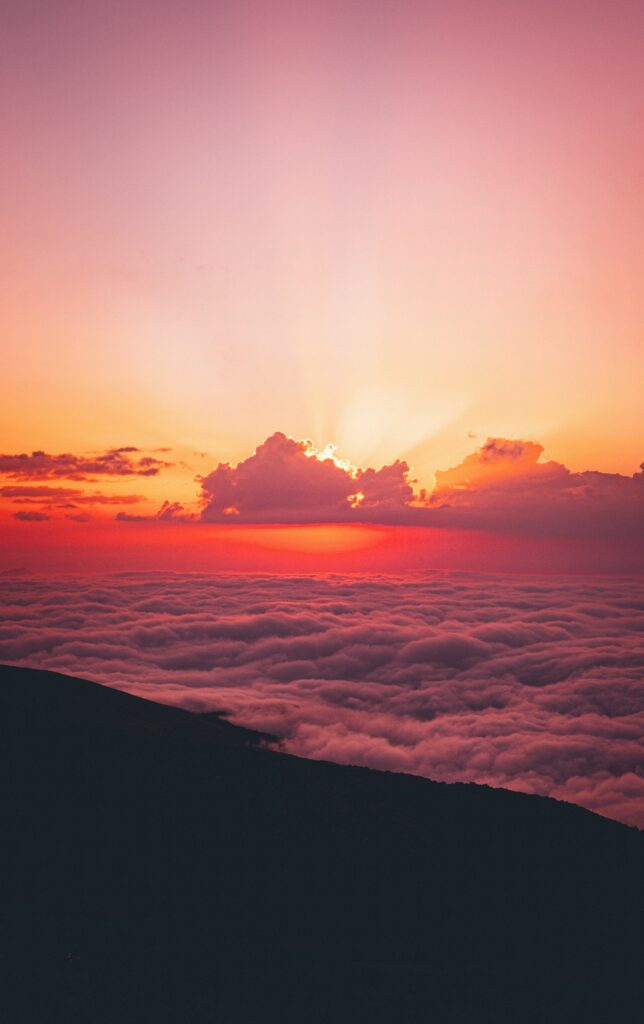 Sunset wallpaper with golden rays through dramatic clouds casting orange pink and purple hues