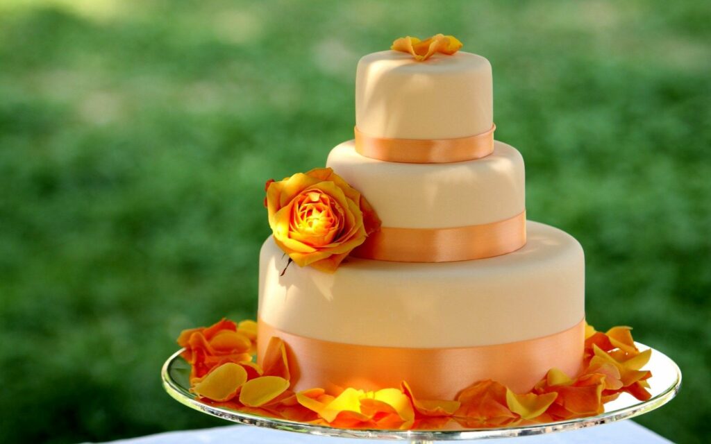 Elegant Three-Tier Wedding Cake with Ivory Icing & Orange Roses Wallpaper