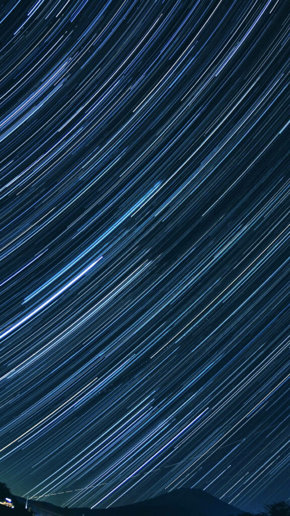 Stellar Nighttime Time-lapse Captures Majestic Star Trails Over Mountain Range as Breathtaking Space Phone Wallpaper