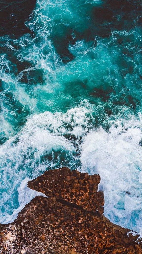 Stunning Aerial Wallpaper: Turquoise Waves & Rocky Shore Background
