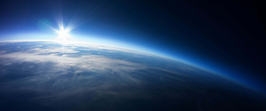 Stunning Ultra-Wide Wallpaper of Earth from Space with Sunbeam