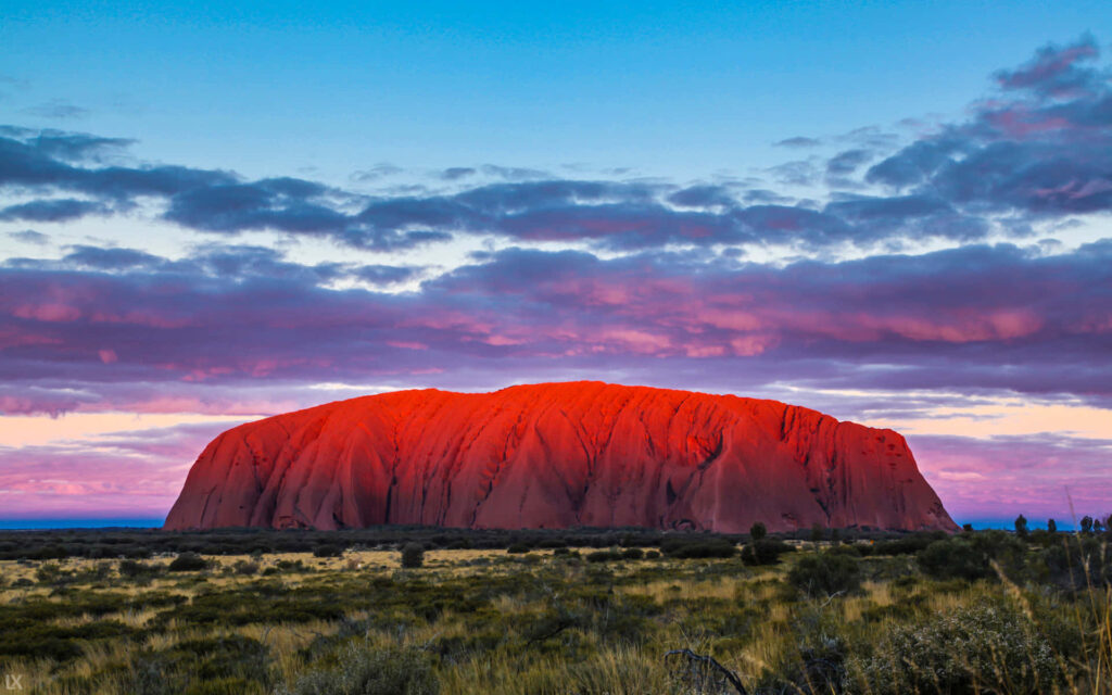 Vibrant Uluru Wallpaper: Red Hues & Dramatic Clouds Background