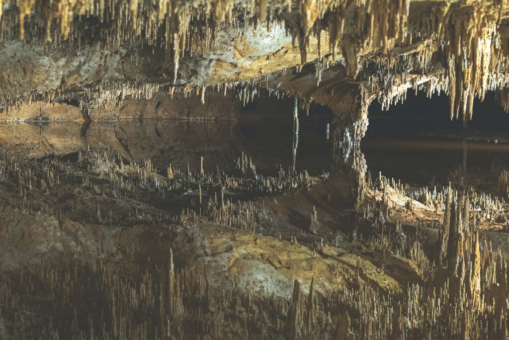 Intricate Stalactites & Stalagmites in a Mystical Cave Background Wallpaper