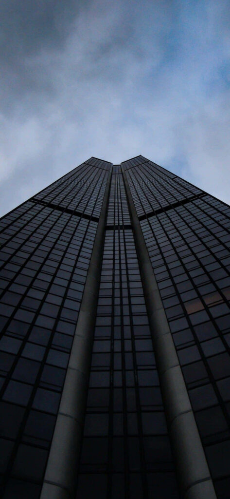 Modern Skyscraper Wallpaper: Towering Design Against Moody Clouds