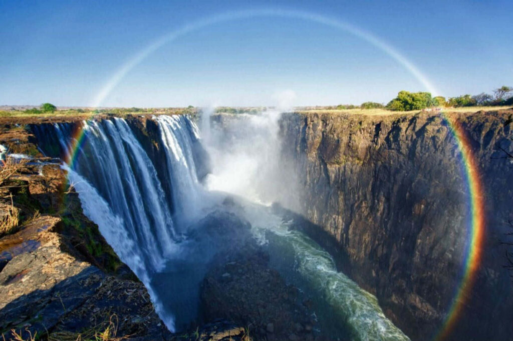 Victoria Falls Wallpaper: Majestic Waterfall with Rainbow & Blue Sky