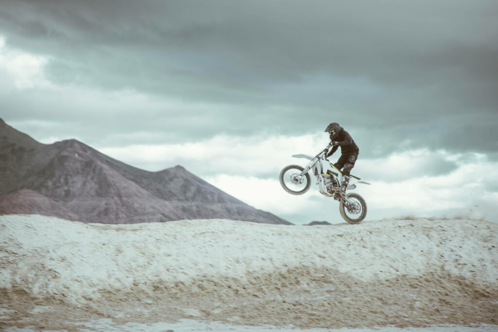 Stunning Motorcyclist Balancing Stunt Wallpaper in Rugged Mountains