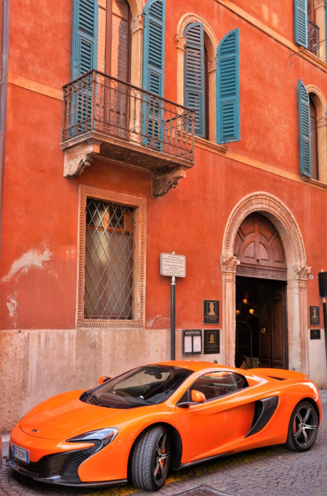 Orange McLaren Supercar Against Rustic Building - Captivating Contrast Wallpaper