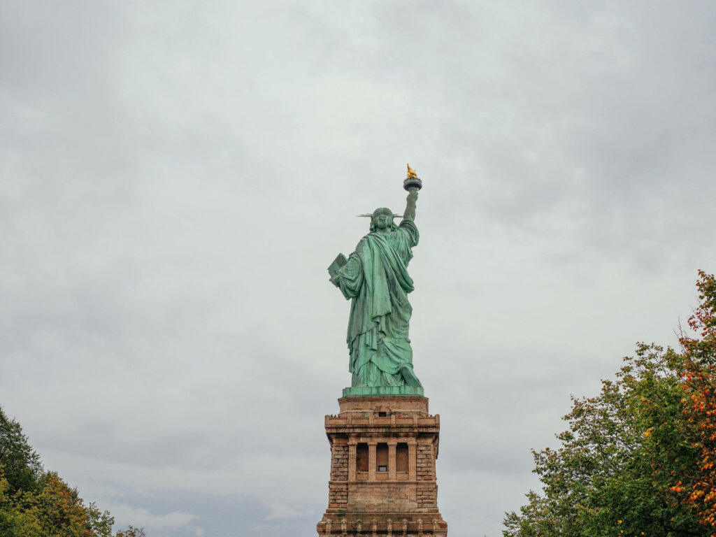 Statue of Liberty Back View: Cloudy Sky Wallpaper Background