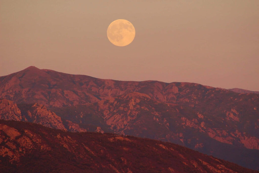 Vibrant Pink Moon Over Rugged Peaks: Serene Dusk Wallpaper