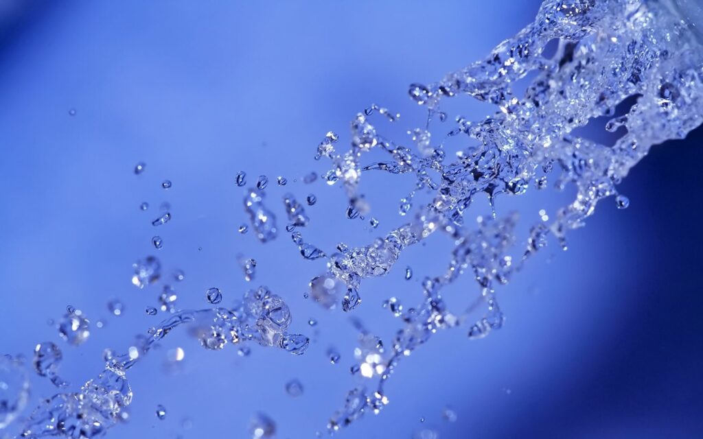 Close-Up Water Spray Wallpaper: Shimmering Droplets & Blue Background