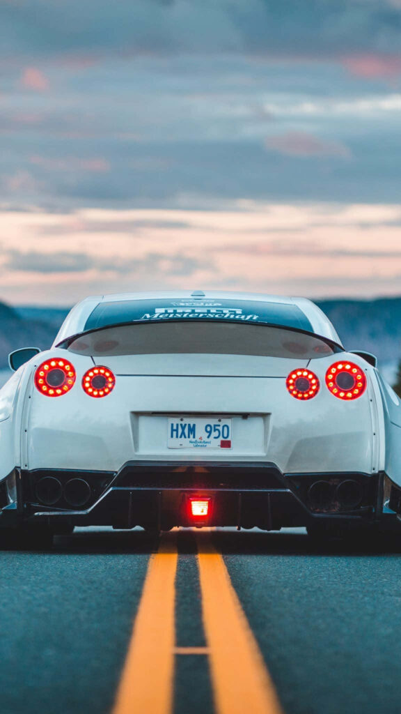 White R33 GTR parked on empty road at dusk with glowing round taillights and dramatic sky wallpaper