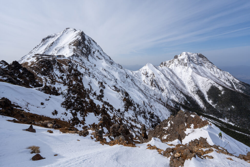 Snow-capped rugged mountains with steep slopes and dark stones under a cloudy alpine sky wallpaper