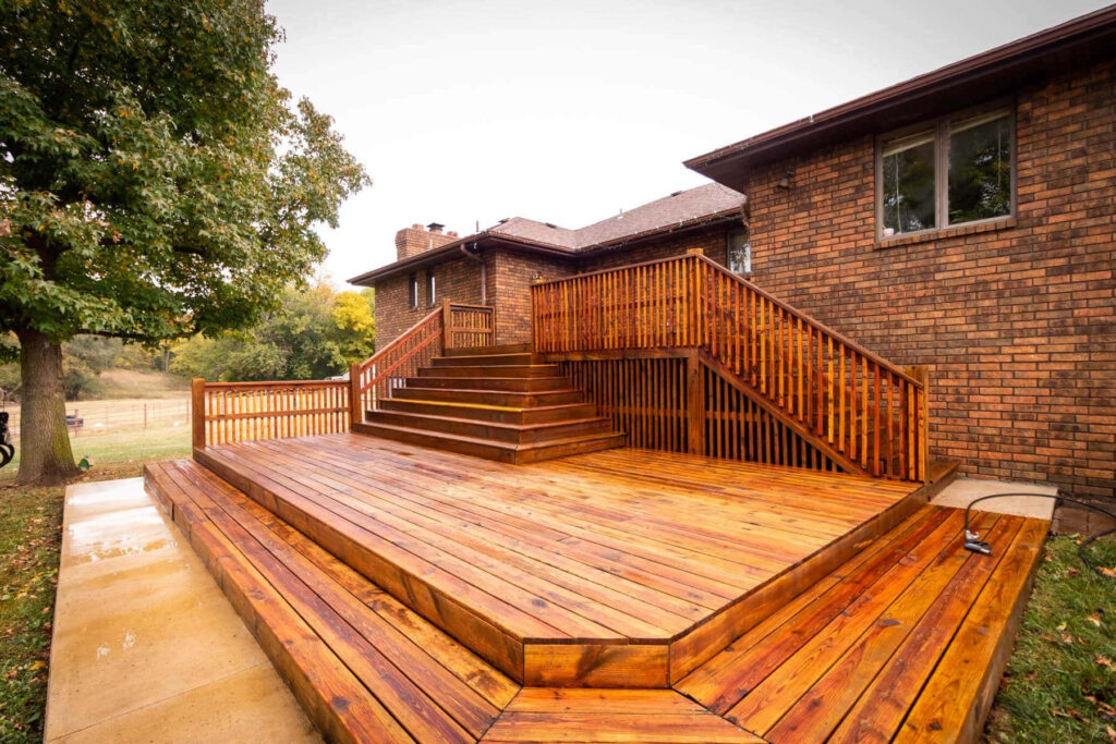 Stunning Multi-Level Wooden Deck Beside Brick House with Lush Greens Wallpaper