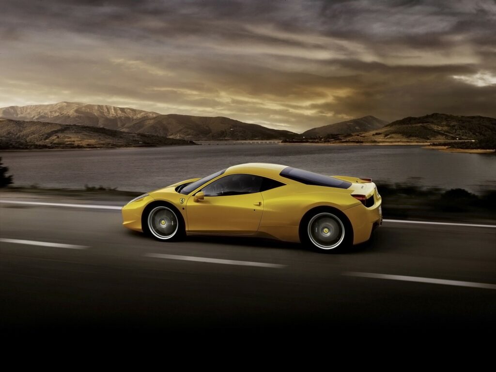Stunning Yellow Ferrari 458 Italia: Dynamic Side View with Scenic Background Wallpaper