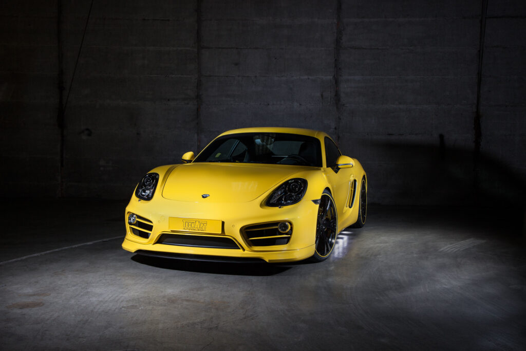 Striking Yellow Porsche Cayman: Sleek Design on Minimalist Background Wallpaper