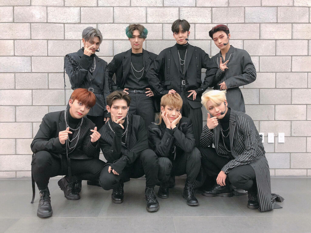 Stylish ATEEZ Wallpaper: Members in Dark Outfits by Brick Wall