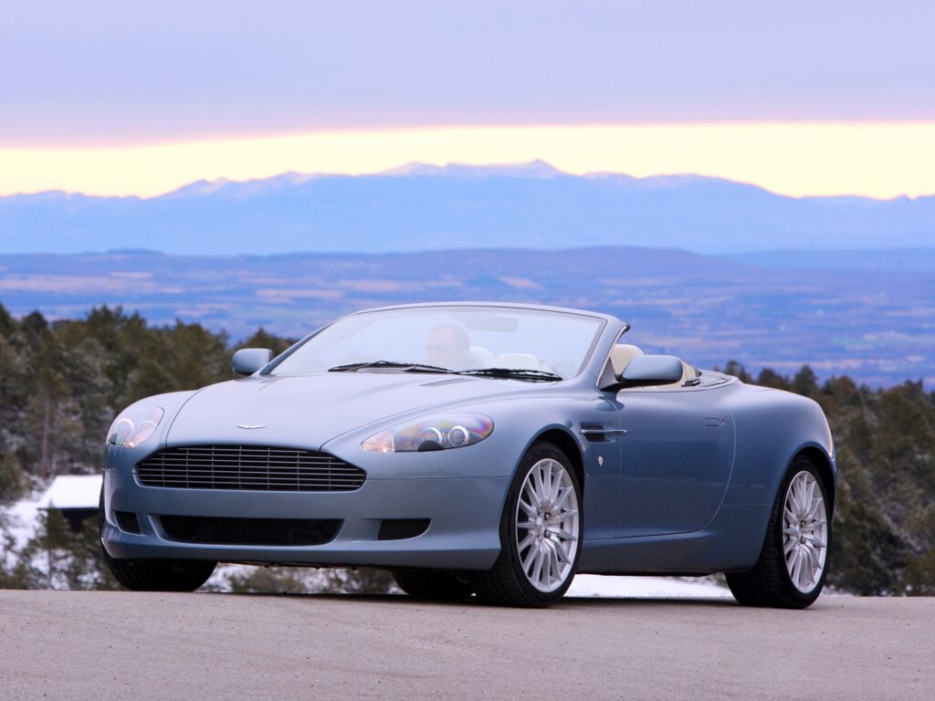 Elegant 2004 Blue Aston Martin DB9 Against Mountain Background Wallpaper