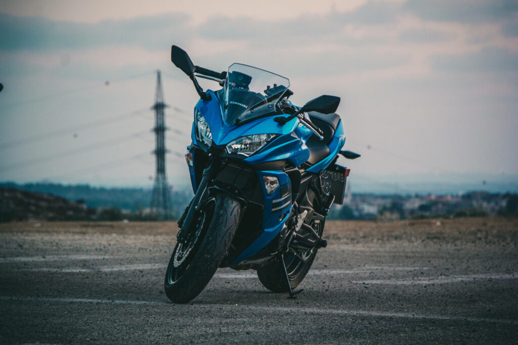 Stylish Blue Motorcycle Wallpaper on Rugged Terrain & Cloudy Sky