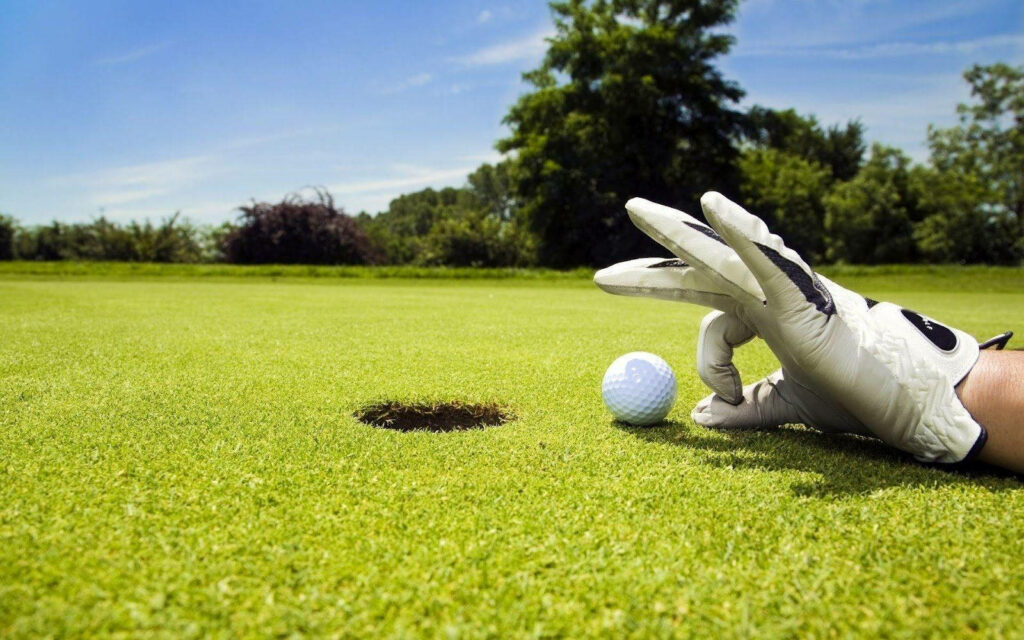 Stylish Golf Wallpaper: Golfer with Glove on Vibrant Green Course