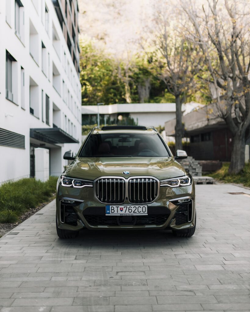 Stunning Green BMW SUV in Urban Setting: Modern Architecture Background Wallpaper