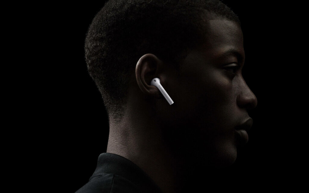 Stylish man wearing Apple AirPods in profile on dark background showcasing modern technology Wallpaper