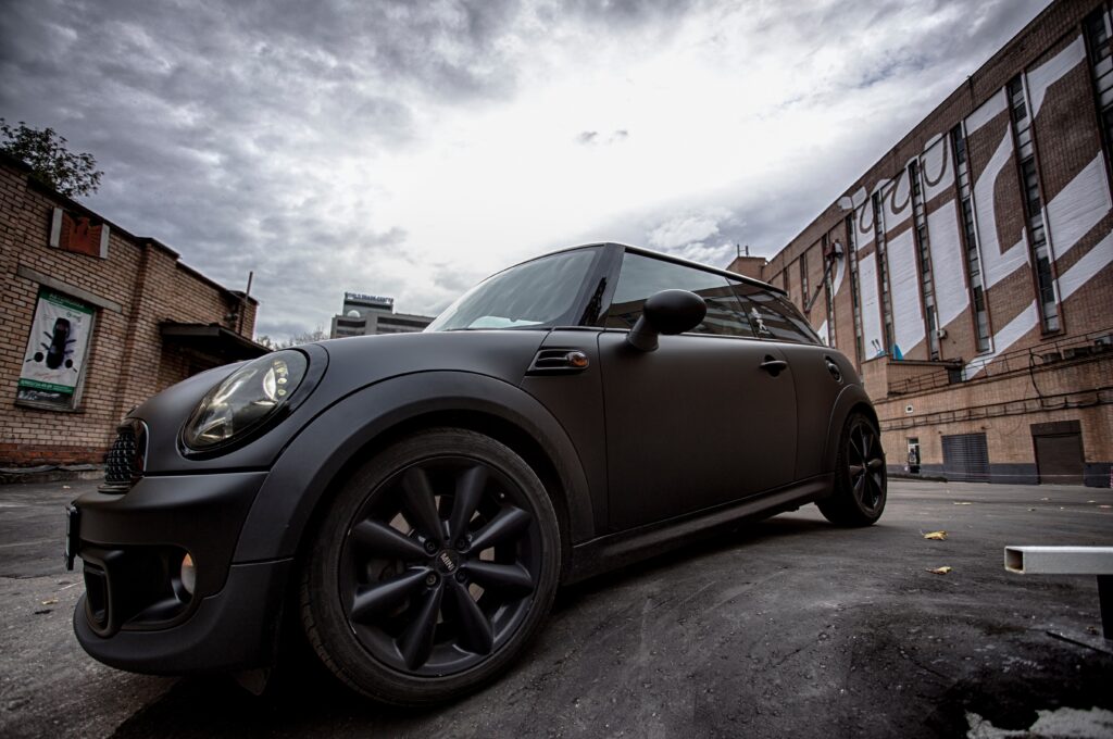 Sleek Matte Black Mini Cooper with Urban Industrial Background Wallpaper