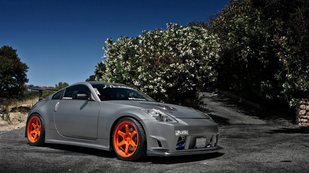 Sleek Nissan 350Z Wallpaper: Vibrant Orange Rims on Scenic Road