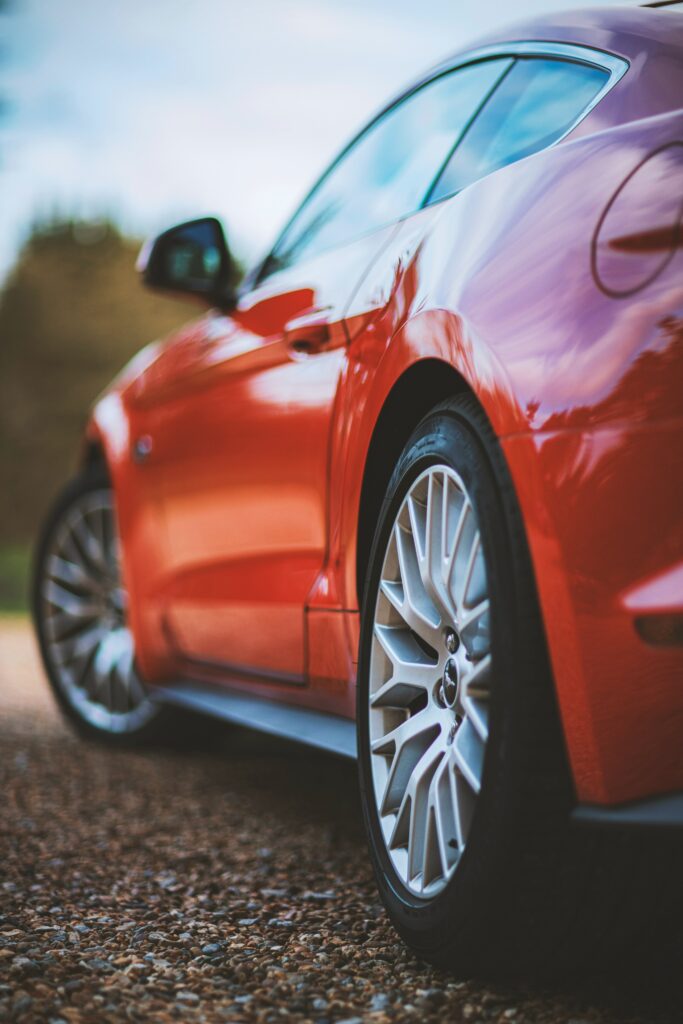 Sleek Red Car Wallpaper: Stylish Wheel & Glossy Finish Outdoors