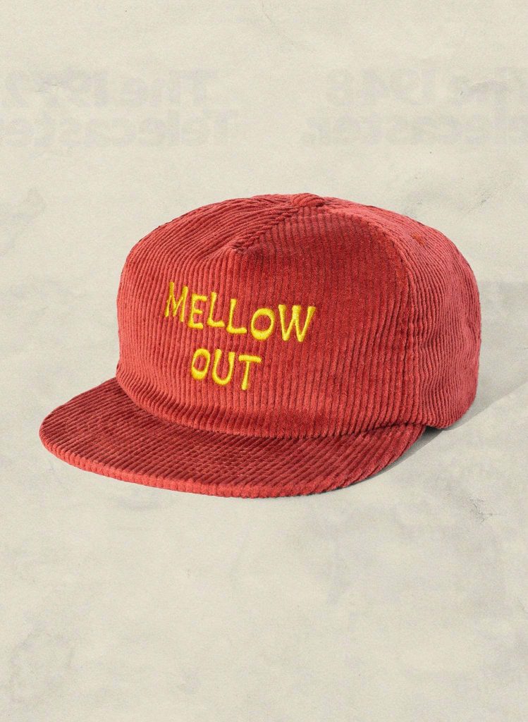 Red corduroy baseball cap with yellow MELLOW OUT embroidery on minimalist off-white background Wallpaper