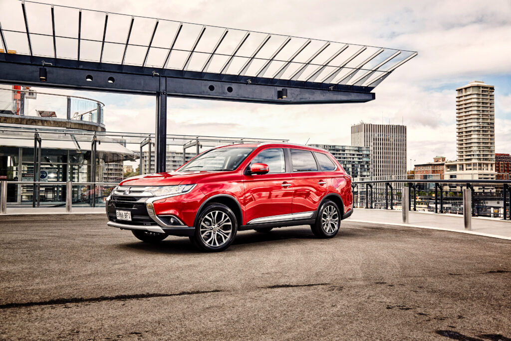 Sleek Red Mitsubishi Outlander: Urban Side View Wallpaper