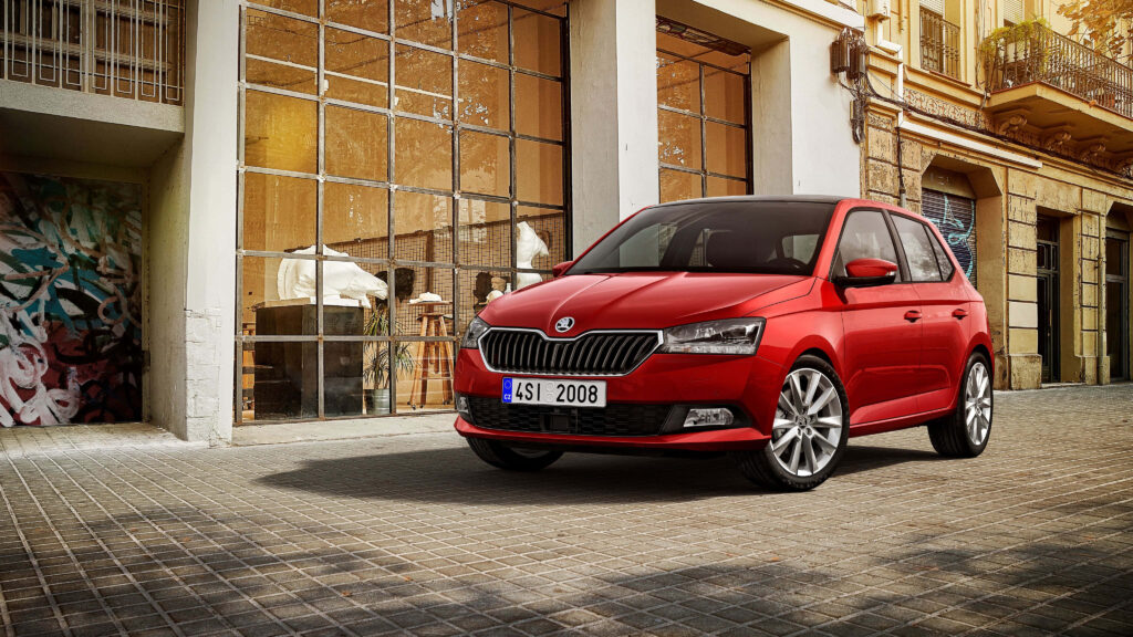 Sleek Red Skoda Fabia Wallpaper Against Urban Backdrop - Stylish Design