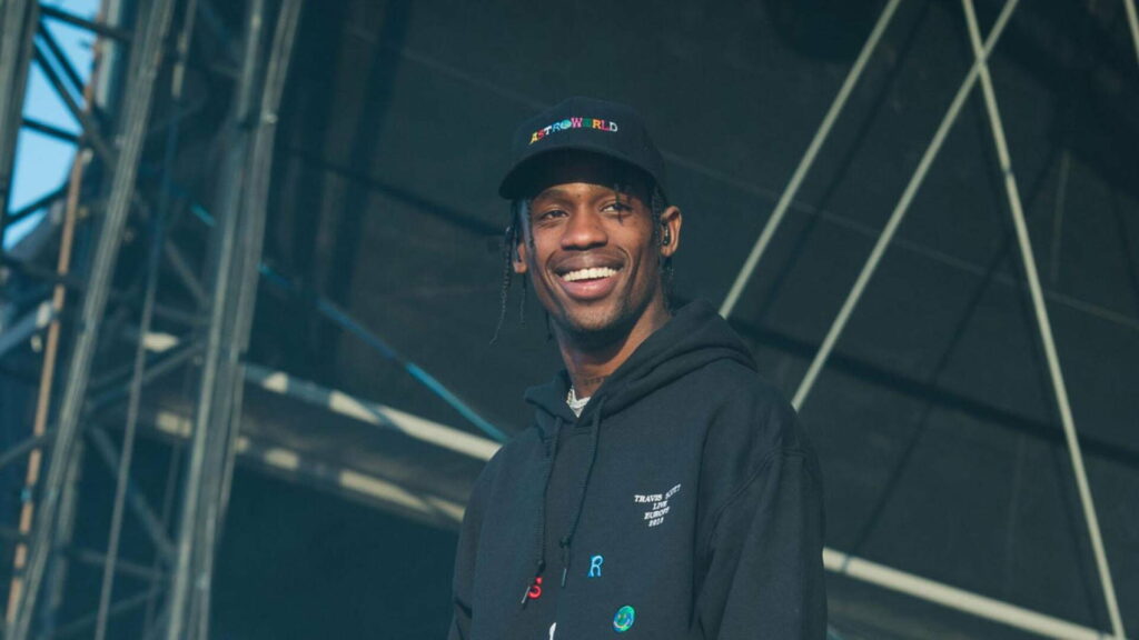 Travis Scott Rocking a Cool Smile in Stylish Black Overcoat and Cap – HD Wallpaper