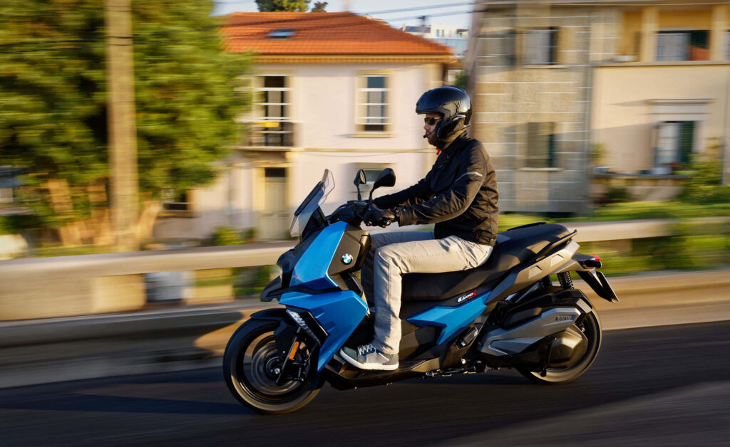 Stylish Commuter: Rider on Blue Scooter in Serene Neighborhood Wallpaper