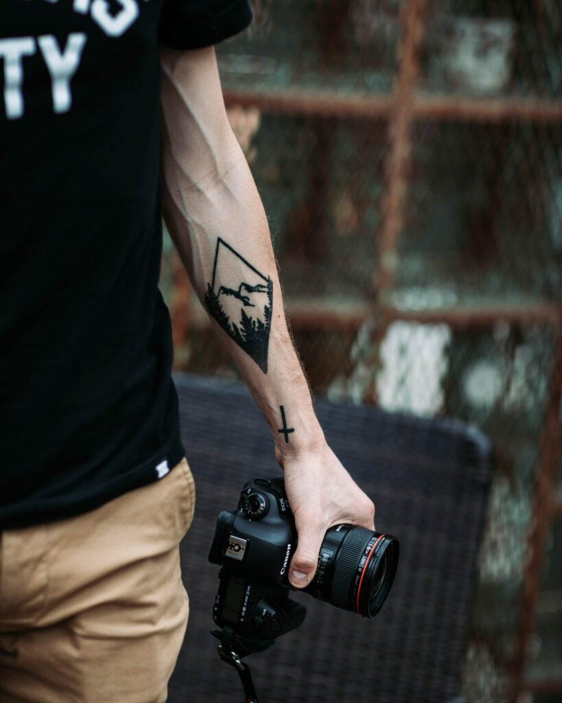 Artistic Wallpaper: Photographer's Tattooed Hand with Camera and Mountains