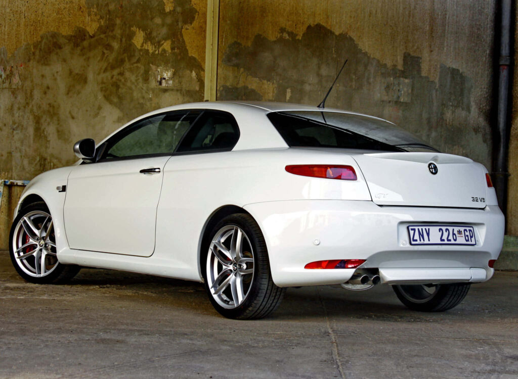 White Alfa Romeo GT parked in industrial area showcasing sporty design and sleek curves wallpaper