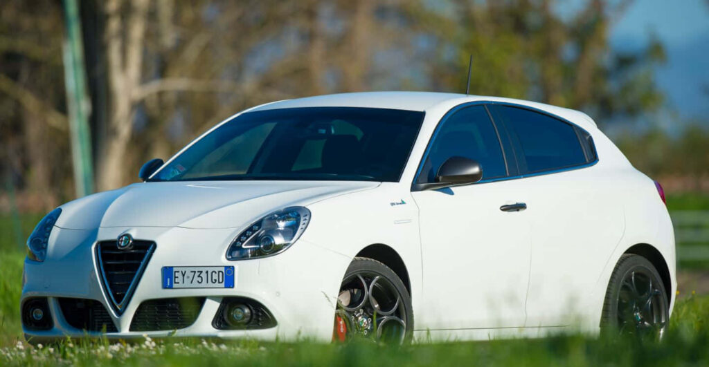 White Alfa Romeo Giulietta sporty car displayed outdoors on a sunny day with natural backdrop Wallpaper