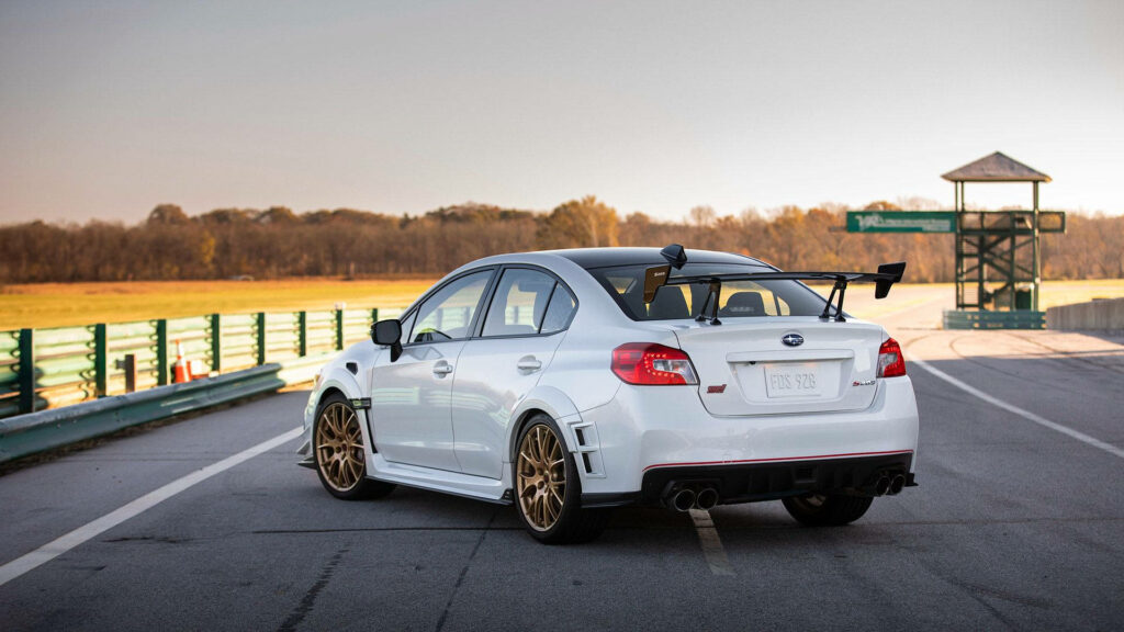 Stylish White Subaru Sedan Wallpaper with Gold Rims & Race Track Vibe