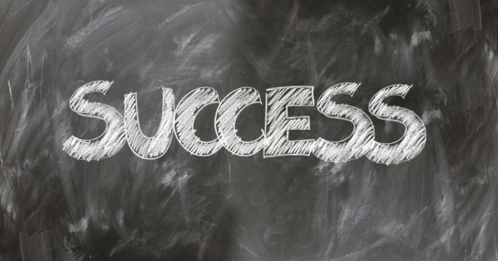 Bold white chalk word Success on dark chalkboard background inspirational wallpaper design