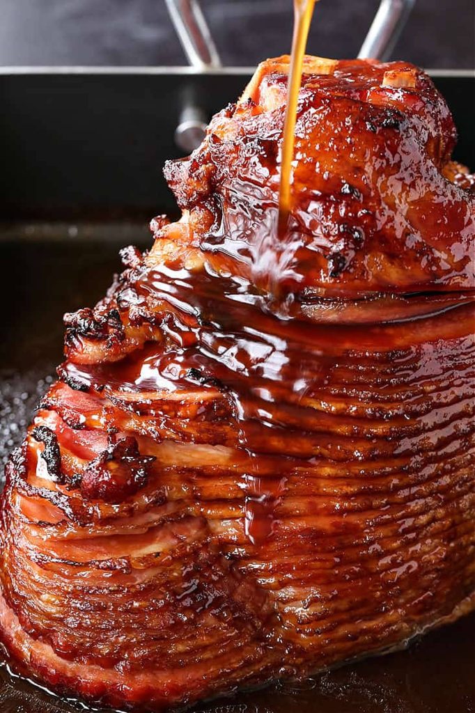 Close-up of spiral-sliced ham with rich glaze pouring over juicy festive meat background Wallpaper