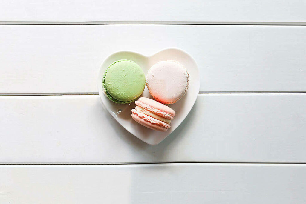 Delicious Indulgence: Adorable Macarons on a Heart-shaped Plate Wallpaper