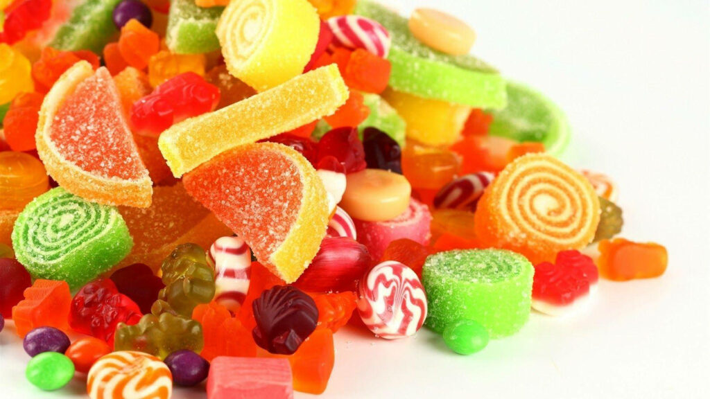 Sugarlicious Rainbow of Variety: Delightful Candy Assortment Captured on a Crisp White Canvas Wallpaper