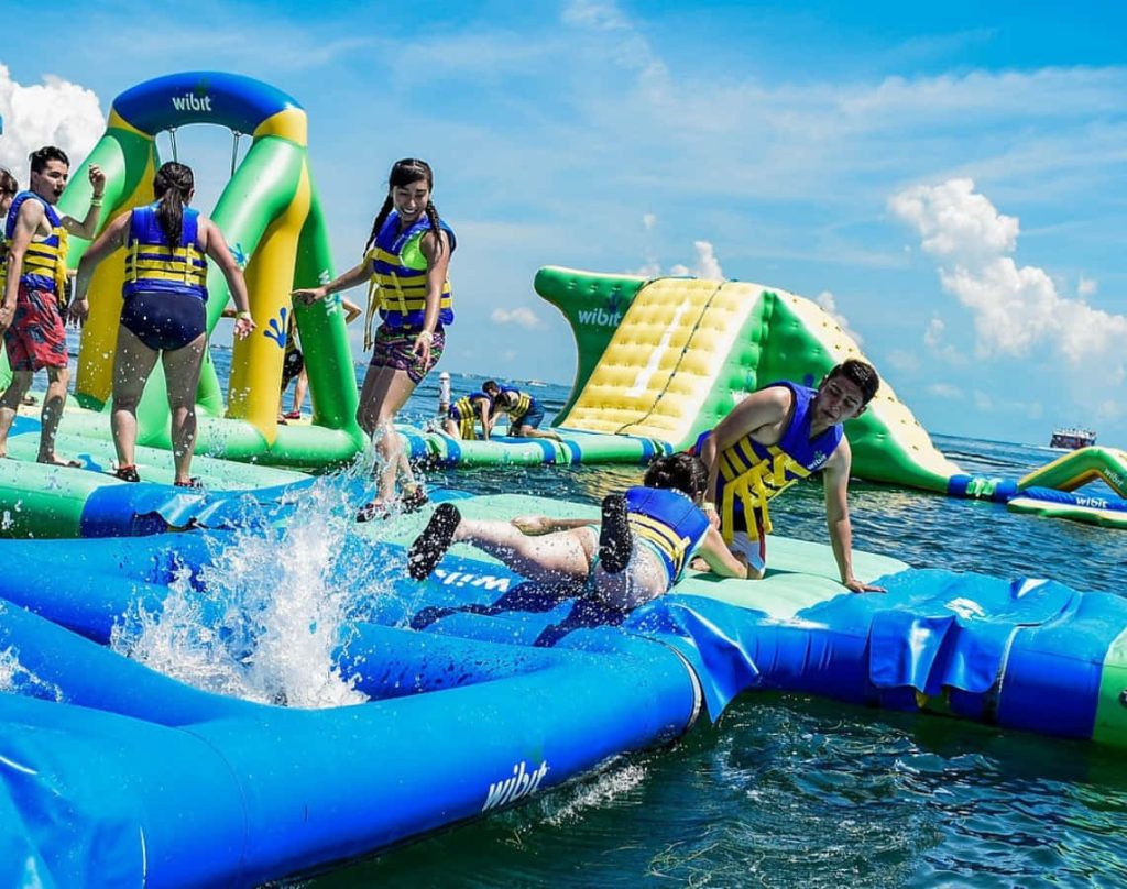 Energetic Wibit inflatable water park with obstacle course on sunny day over sparkling water Wallpaper