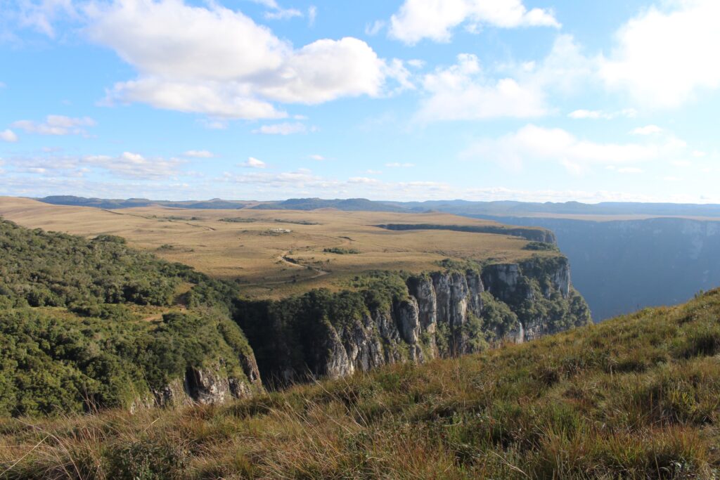 Summer landscape wallpaper with rolling grasslands cliffs distant mountains bright blue sky