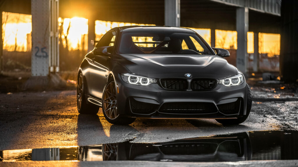 Radiant Black Beast: The BMW M4 GTS commands attention in a deserted parking lot, bathed in sunlight Wallpaper