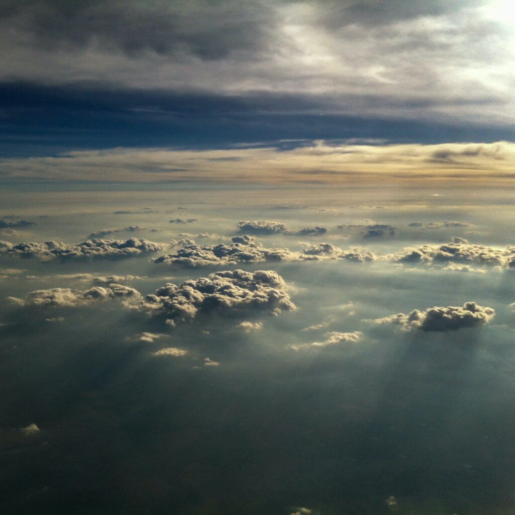 Sun rays break through dense clouds under a vibrant sky creating a serene light and shadow scene Wallpaper