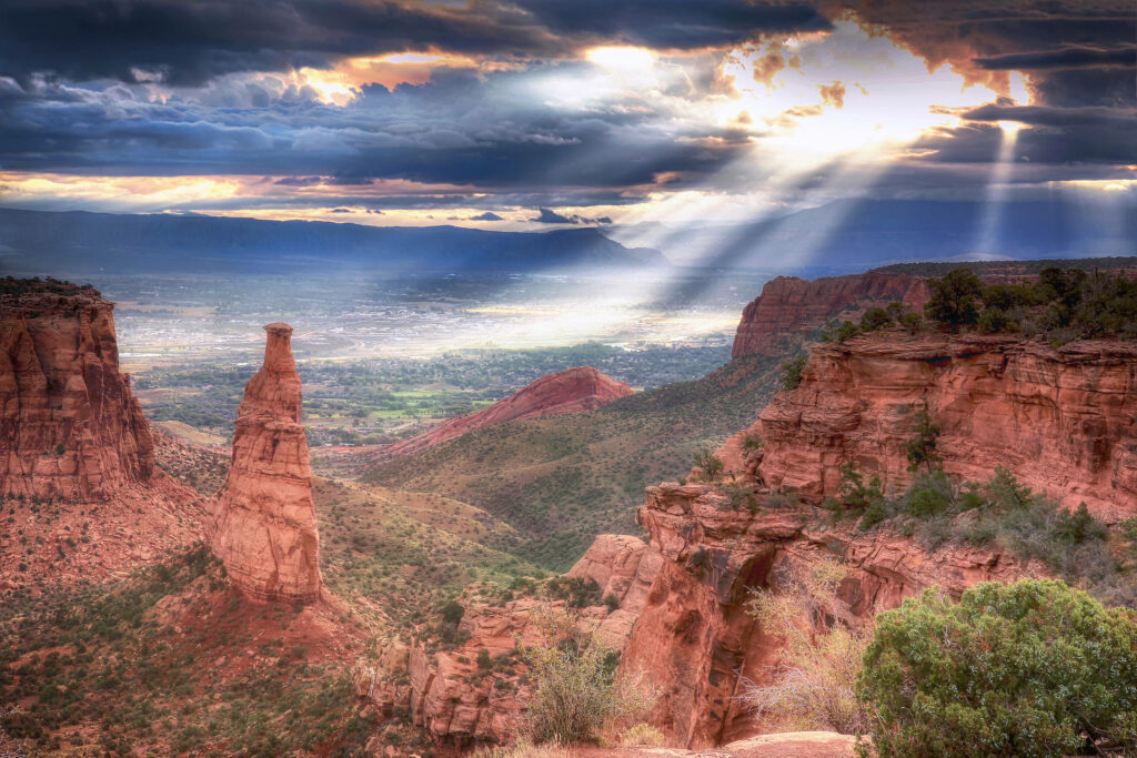 Sunbeams illuminating rugged red rock formations at Colorado National Monument landscape view Wallpaper