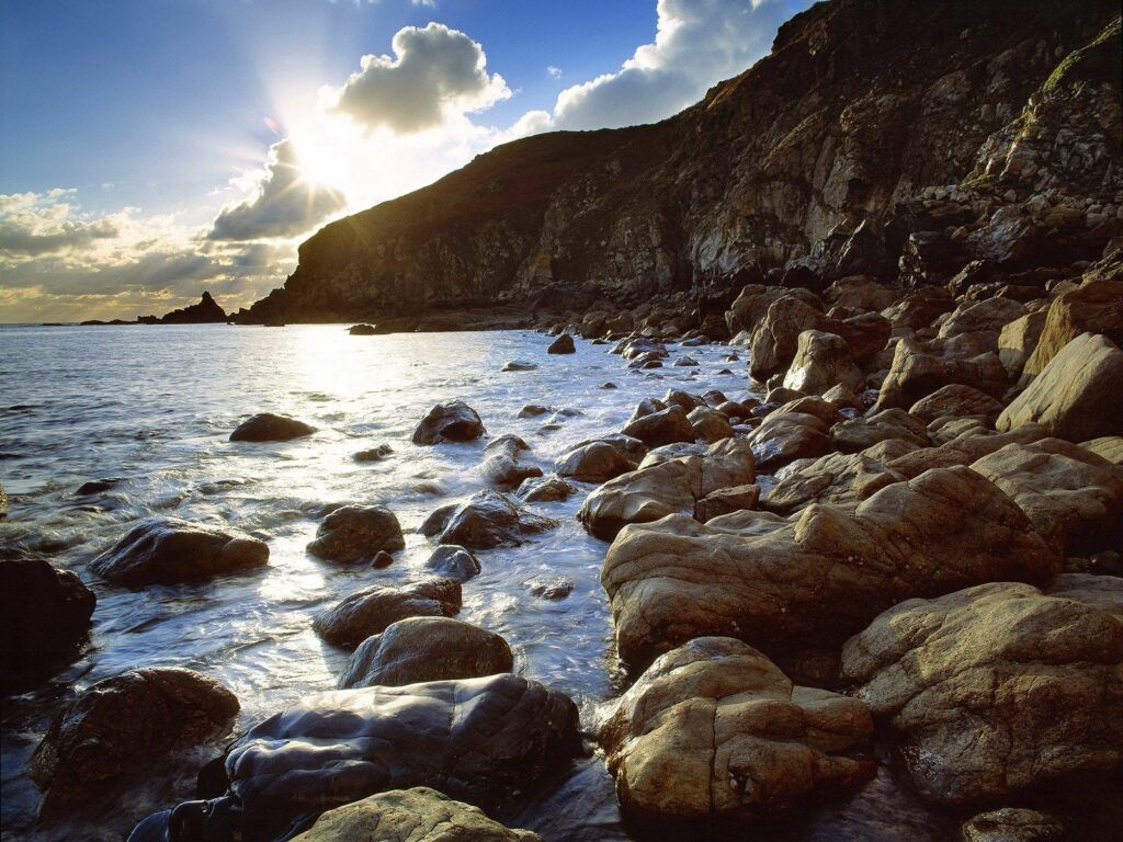 Sunlight over Icelandic rocky coast smooth wet stones blue sea splashes serene natural scene wallpaper