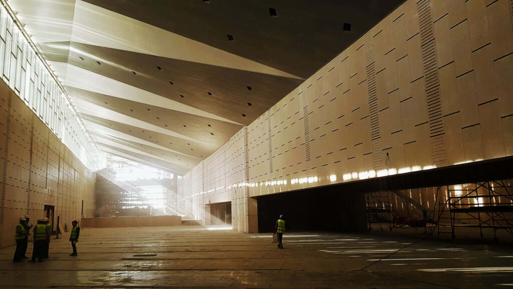 Sunlight through geometric panels casts patterns in Grand Egyptian Museum modern interior under construction Wallpaper