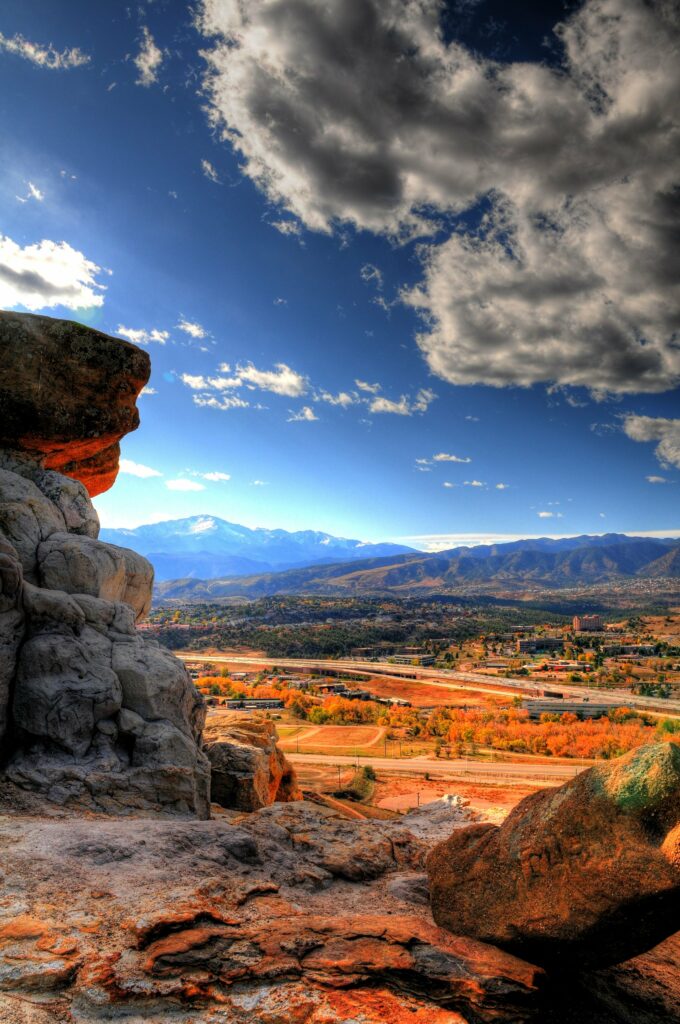 Rugged rocks and winding road lead through autumn mountains under vibrant blue sky wallpaper